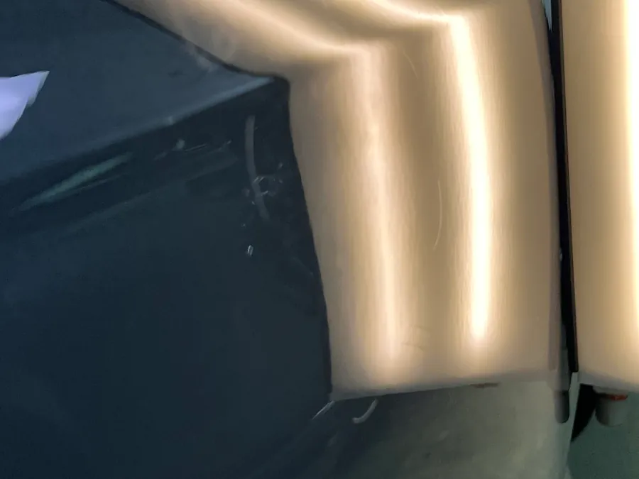 A grey door with the dent light reflected across a repair in progress